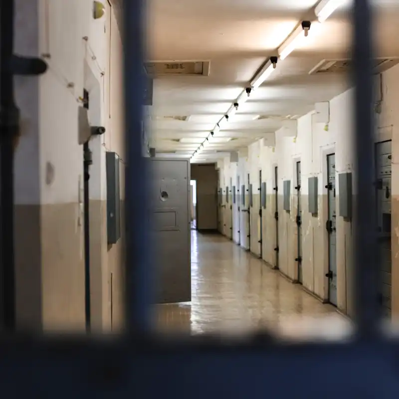 A jail hallway, as viewed through prison bars.