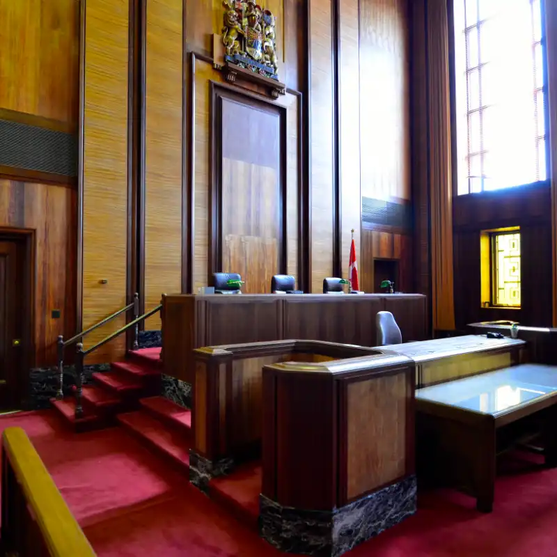An interior shot of a courtroom with wood panels and red carpet.