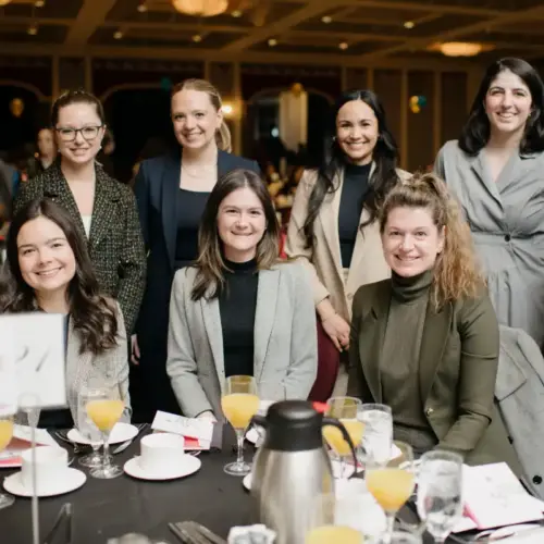 A group of Equality Breakfast attendees smile while sitting at a table.