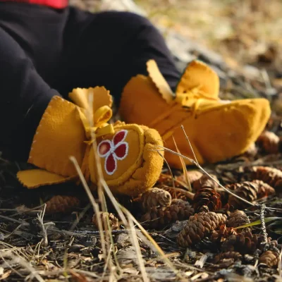 A small child wearing yellow moccasins.