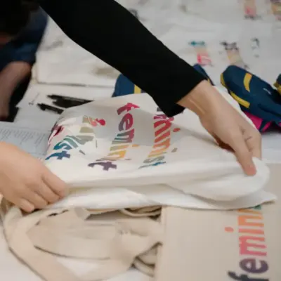 A volunteer is folding a shirt that reads "feminist".
