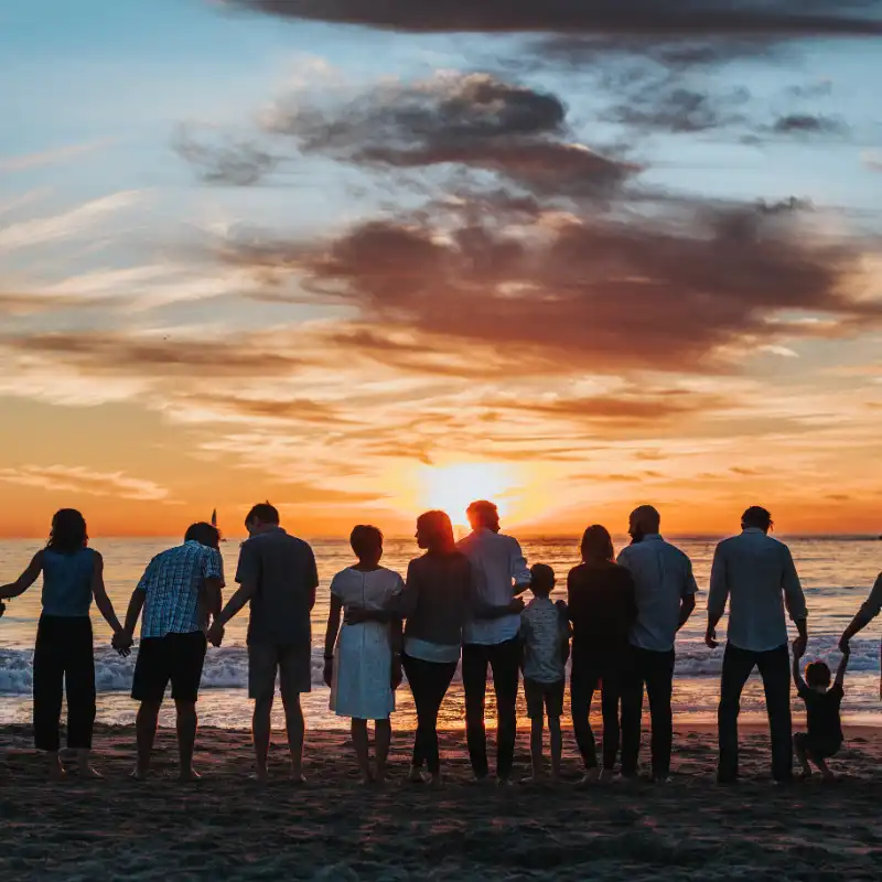 A group of people are watching a sunset on a beach.