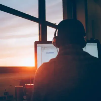 A person wearing headphones is looking at a computer monitor.