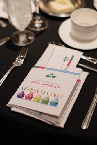 A place setting at the Breakfast, including an event program celebrating 35 years with cupcakes on the cover.