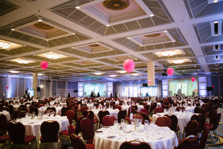 A wide shot of the Fairmont Hotel Vancouver banquet room with several tables with pink balloons.