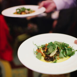 A plate of beautiful-looking salad is carried through the banquet hall.