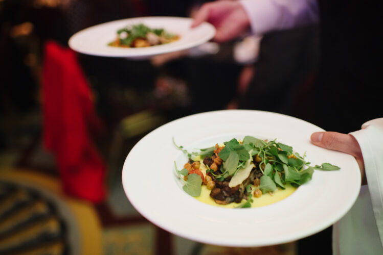A plate of beautiful-looking salad is carried through the banquet hall.