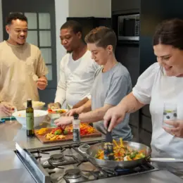 A group of people are cooking in a kitchen and laughing.