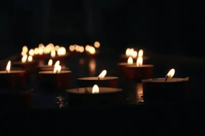 Several lit tea light candles glow in a dark room.