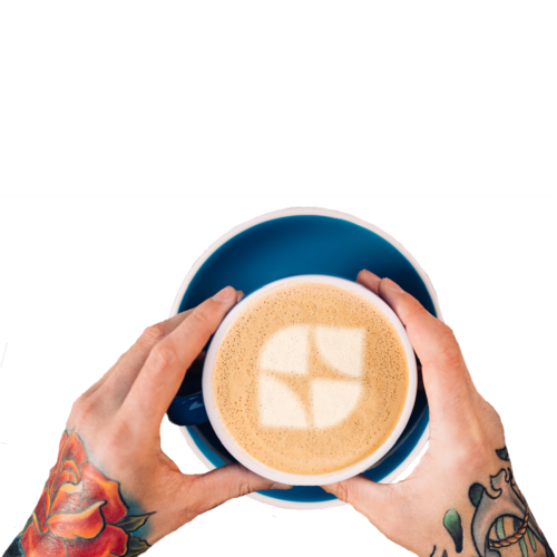 Tattooed hands holding a cappuccino with the West Coast LEAF logo in the foam.