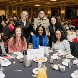 A group of attendees from Harper Grey LLP sit around a table smiling.