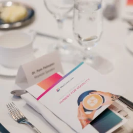 A close up of the table setting, including the cover of the event program, featuring a latte with the foam in the shape of West Coast LEAF's logo.